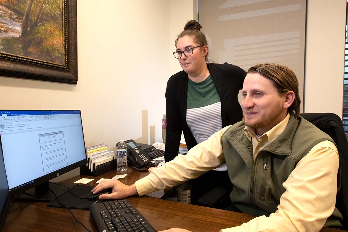 two individuals in front of a computer monitor