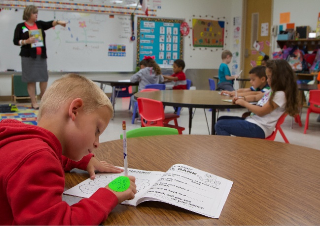 a teacher in a classroom full of kids.