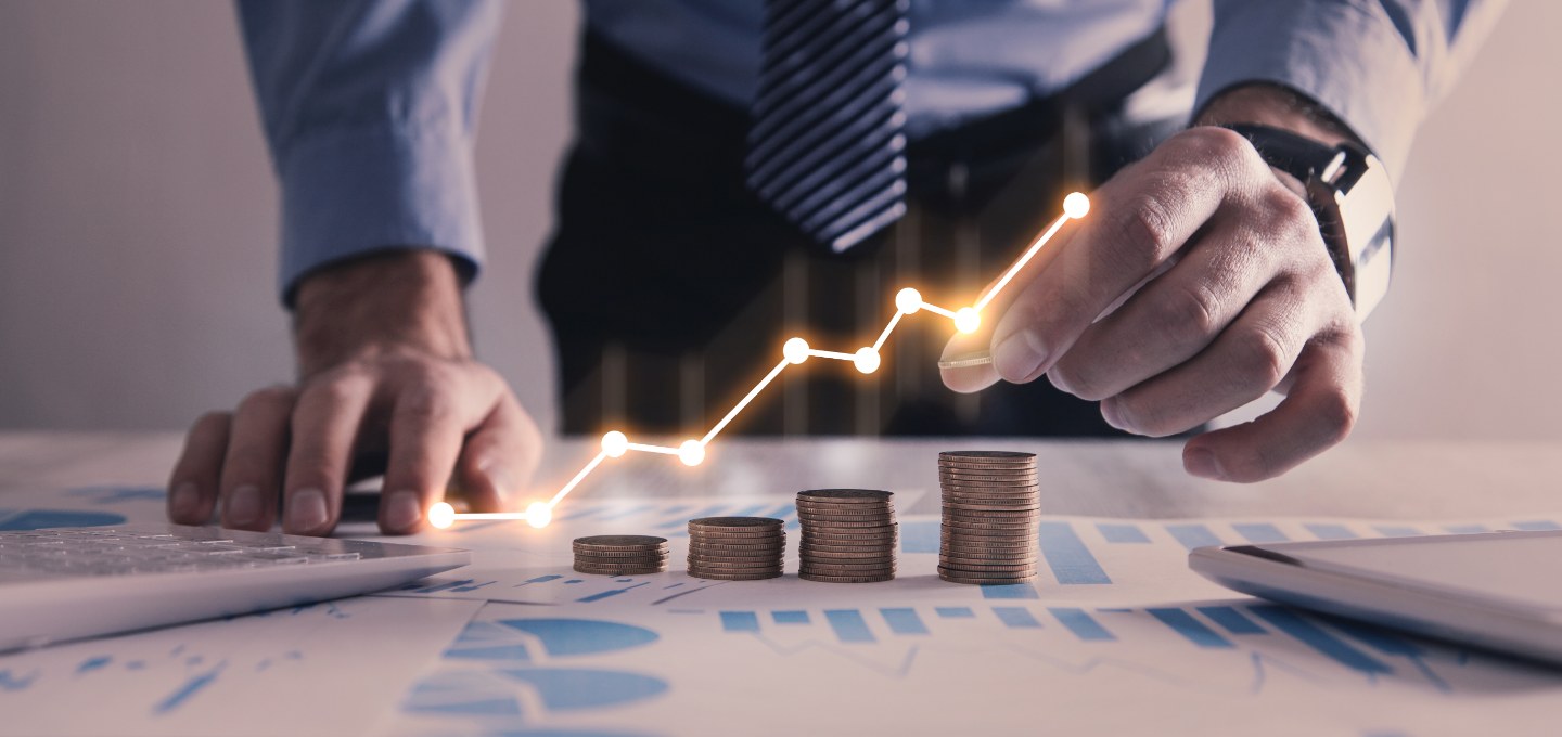 businessman stacking coins on pie and chart graphs