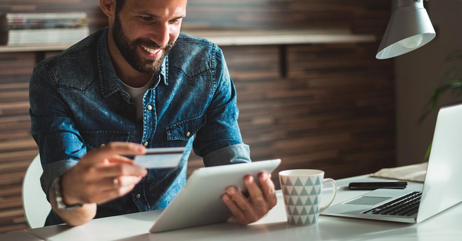 Man in his home business office using a credit card