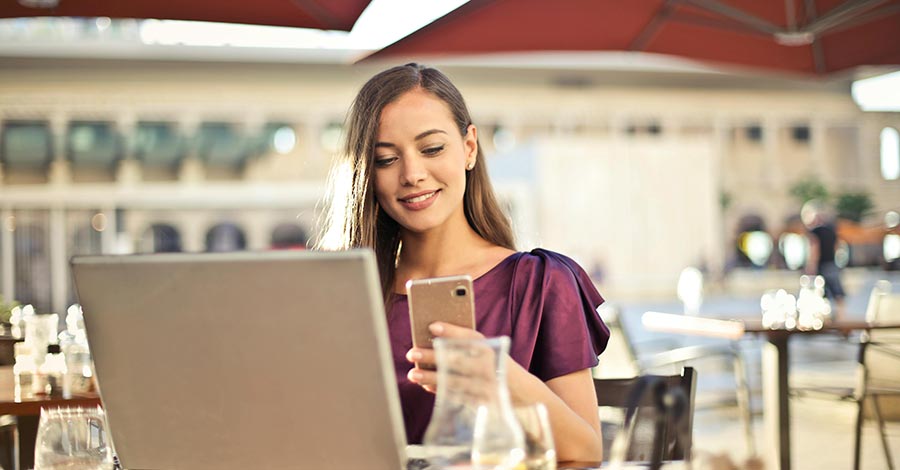 Young lady using a mobile phone and laptop computer in a restaurant