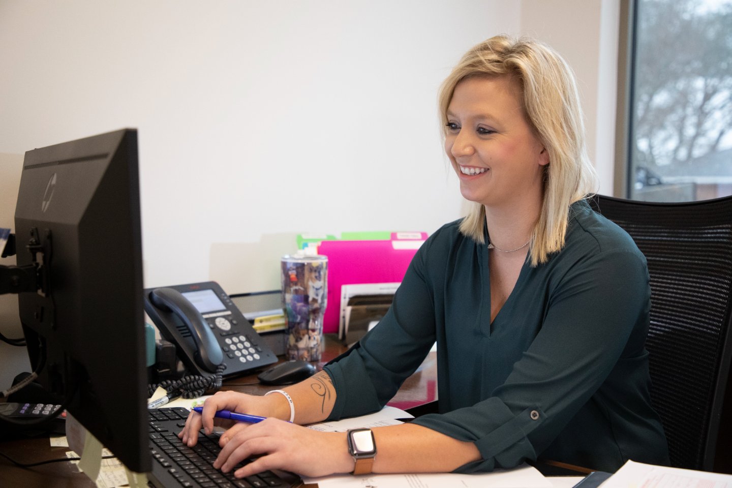 a woman at her desk viewing her desktop computer.