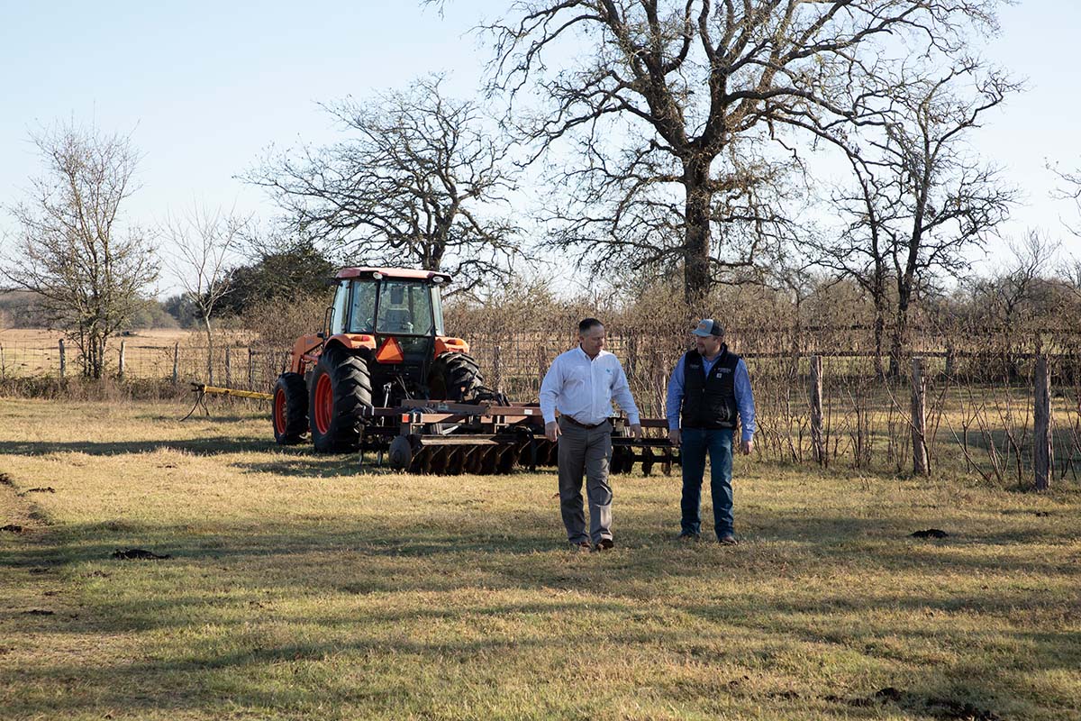two men walking with a tractor behind them