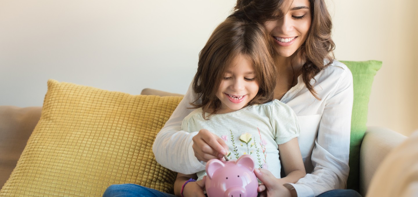 a mother and daughter putting coins in a piggy bank